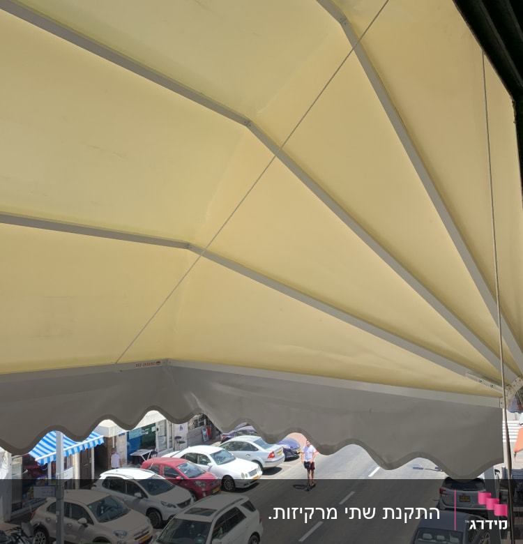 סוכך צהוב עם קצוות גליים מעל רחוב